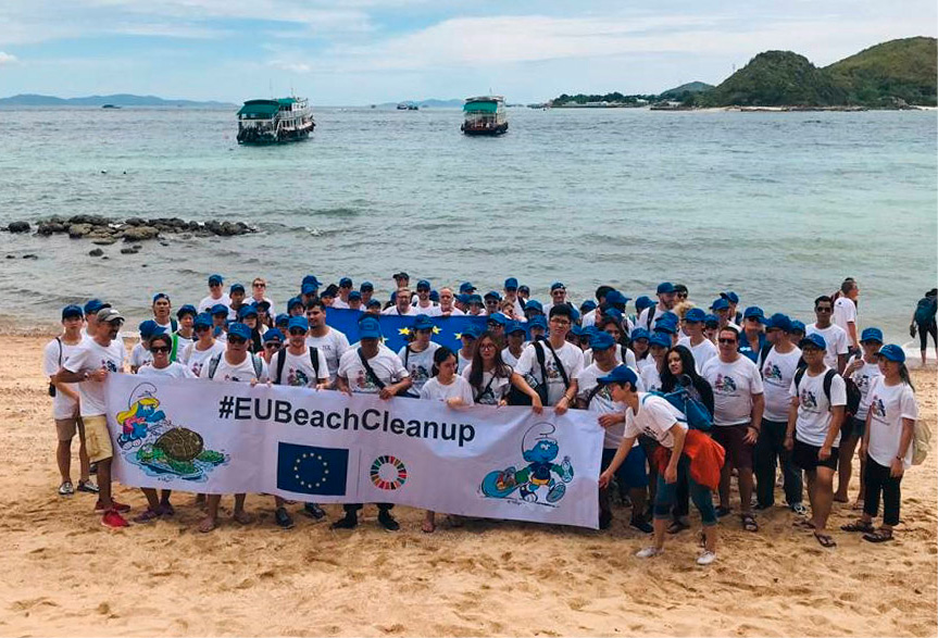 Skupina ľudí na pláži drží banner s nápisom „#EUBeachCleanUp“