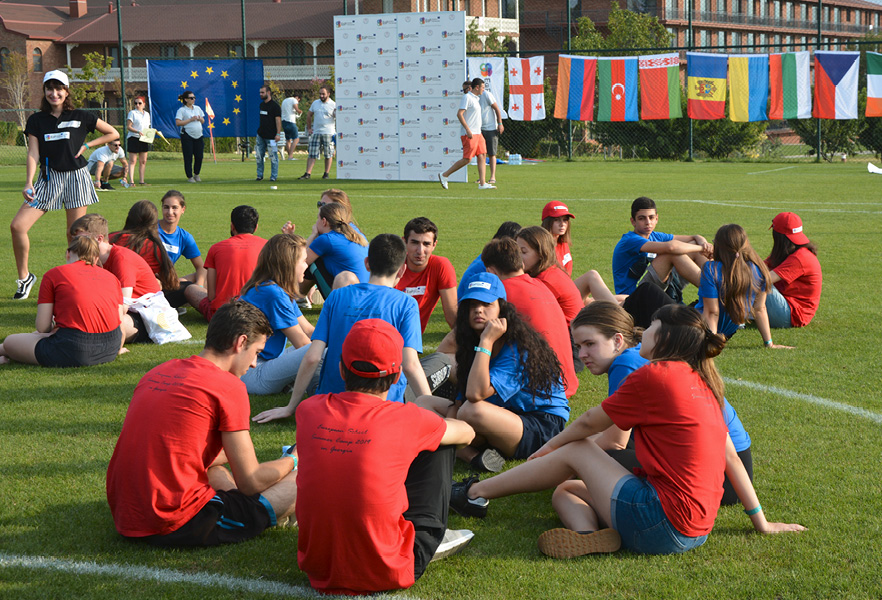 Een groep jongeren zit op een sportveld