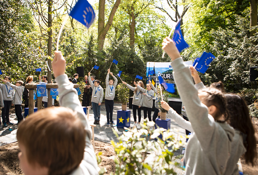Kinderen in schooluniformen wapperen in een park met Europese vlaggetjes