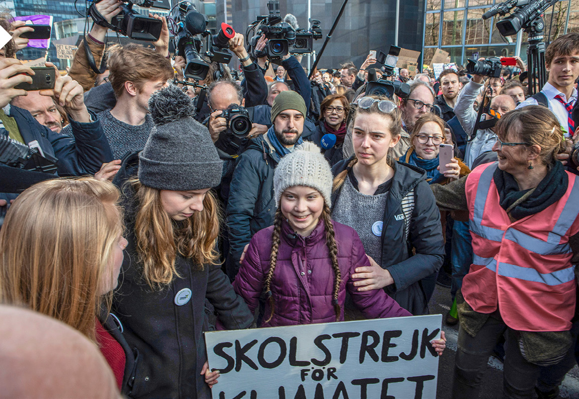 Greta Thunberg na čele demonštrácie, v rukách drží banner so sloganom „školský štrajk za klímu“ 
