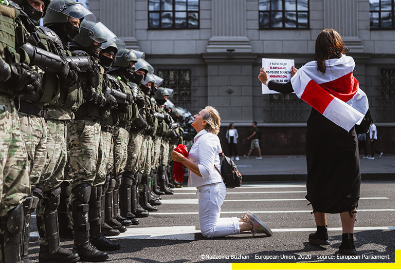 Een vrouw knielt als protest voor een peloton van de Belarussische oproerpolitie. © Nadzeia Buzhan — Europese Unie, 2020 — Bron: Europees Parlement.