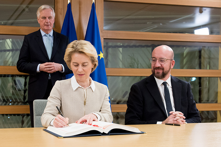 Ursula von der Leyen en Charles Michel ondertekenen het terugtrekkingsakkoord tussen de EU en het Verenigd Koninkrijk, met Michel Barnier op de achtergrond.