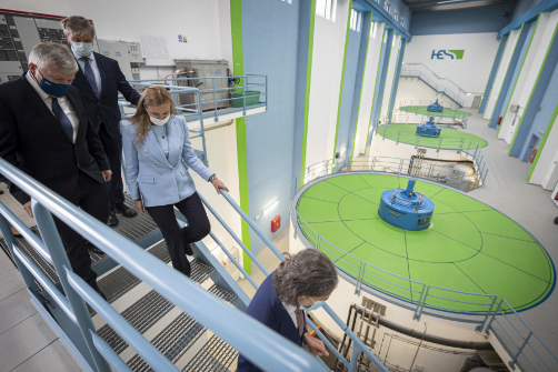 Kadri Simson and others walking down the stairs inside a large factory.