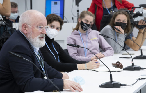 Frans Timmermans speaking at a round-table discussion in front of a group of youth activists wearing masks.