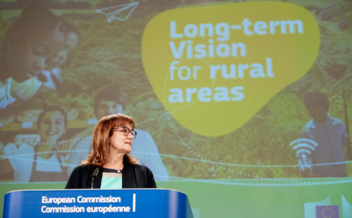 Dubravka Šuica pri rečníckom pulte, v pozadí je plagát ilustrujúci dlhodobú víziu EÚ pre vidiecke oblasti.