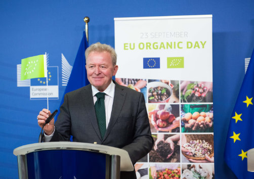 Janusz Wojciechowski en el estrado, delante de un cartel sobre el Día de la Producción Ecológica de la Unión Europea.