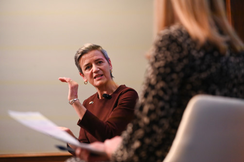 Margrethe Vestager gesturing while in conversation with another person.