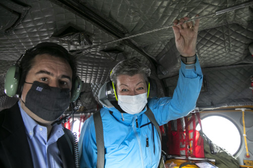 Ylva Johansson et Notis Mitarachi, portant tous les deux un masque et un casque radio, à bord d’un hélicoptère.