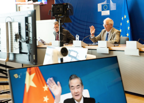 Josep Borrell waves at the camera while Wang Yi waves back on screen.