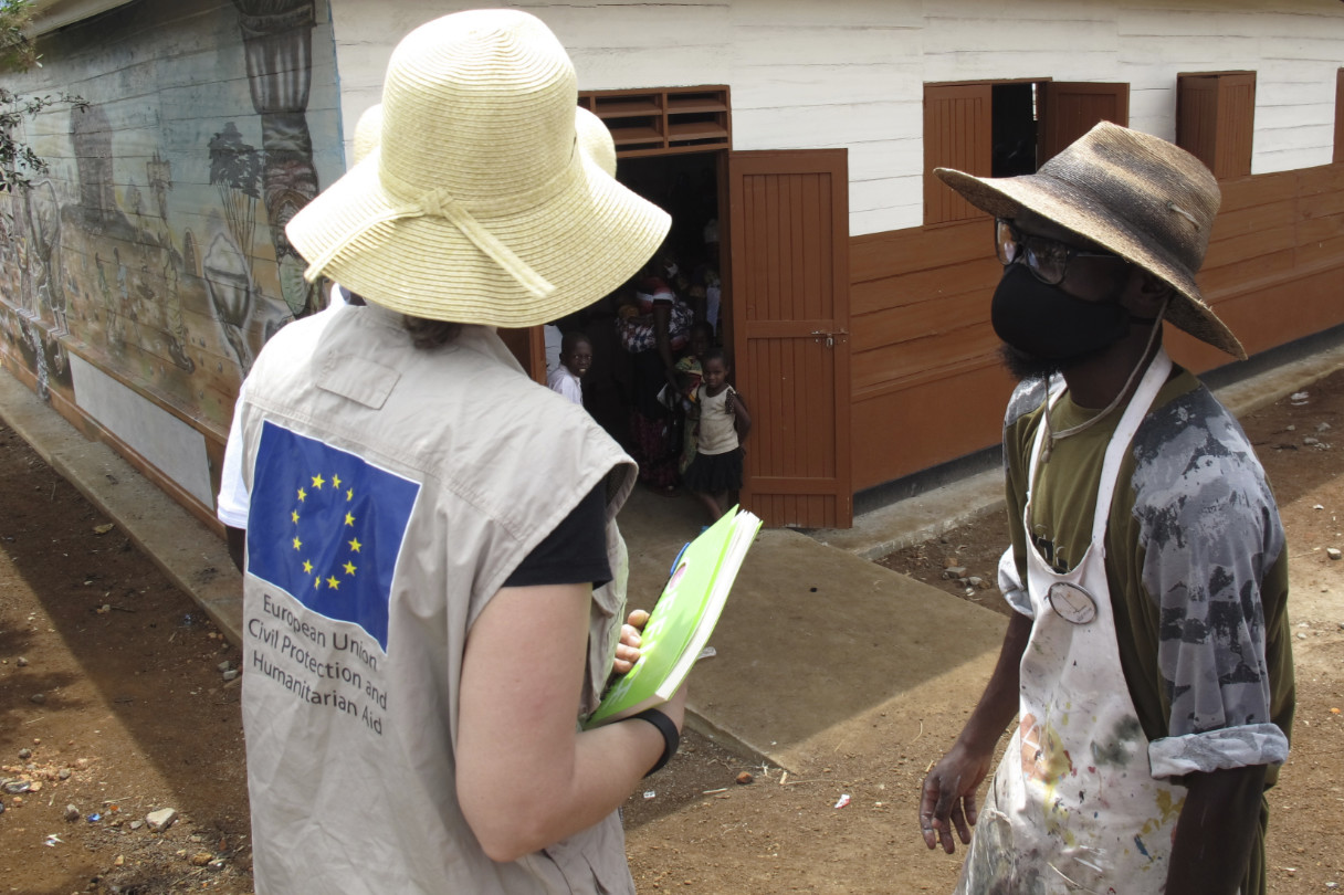 Two aid workers in conversation in front of a reception centre.