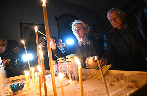 Josep Borrell and Ursula von der Leyen light candles while being filmed by photographers in the background.
