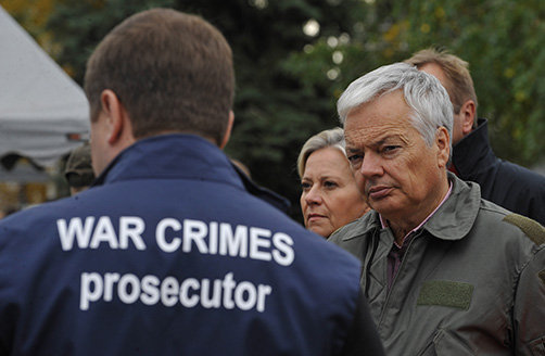 Selin kameraan Andriy Kostin, yllään liivi, jossa lukee ”War Crimes Prosecutor”, ja hänen oikealla puolellaan Didier Reynders kasvot kameraan päin.