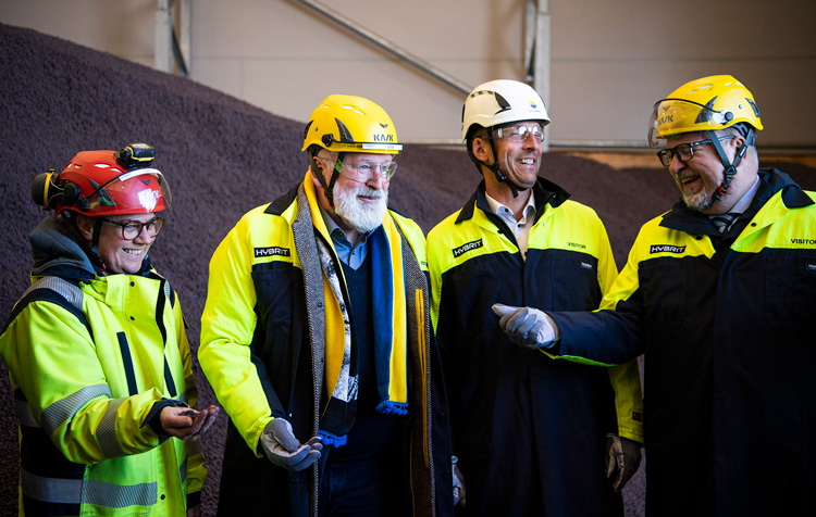 Frans Timmermans indossa una tuta protettiva e un casco all’interno di una fabbrica.