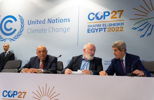 Sami Szukri, Frans Timermans i Dżon Kery siedzą obok siebie, w tle za nimi plakat o en zet dotyczący zmiany klimatu z napisem „Kop dwadzieścia siedem Szarm el Szeik Egipt dwa tysiące dwadzieścia dwa”.