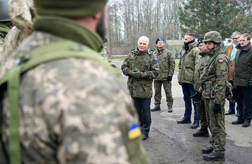 Karinę uniformą vilkintis Žosepas Borelis stovi tarp karių.