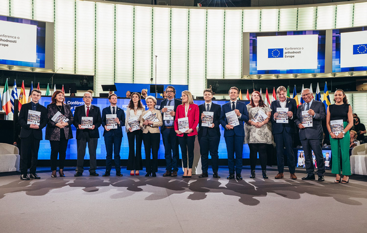 O fotografie de grup în care apar 14 persoane, inclusiv Ursula von der Leyen, Roberta Metsola, Emmanuel Macron și Dubravka Šuica, fiecare ținând în mână un raport privind rezultatele conferinței.