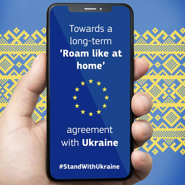 Ein Smartphone-Bildschirm mit den Worten „Towards a long-term ‚Roam like at home‘ Agreement with Ukraine – #StandWithUkraine“ auf blauem Hintergrund und den zwölf im Kreis angeordneten Sternen der Europaflagge.