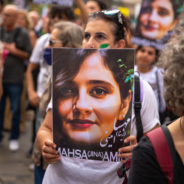 Eine Gruppe Demonstranten mit Plakaten, die das Foto von Mahsa Amini zeigen.