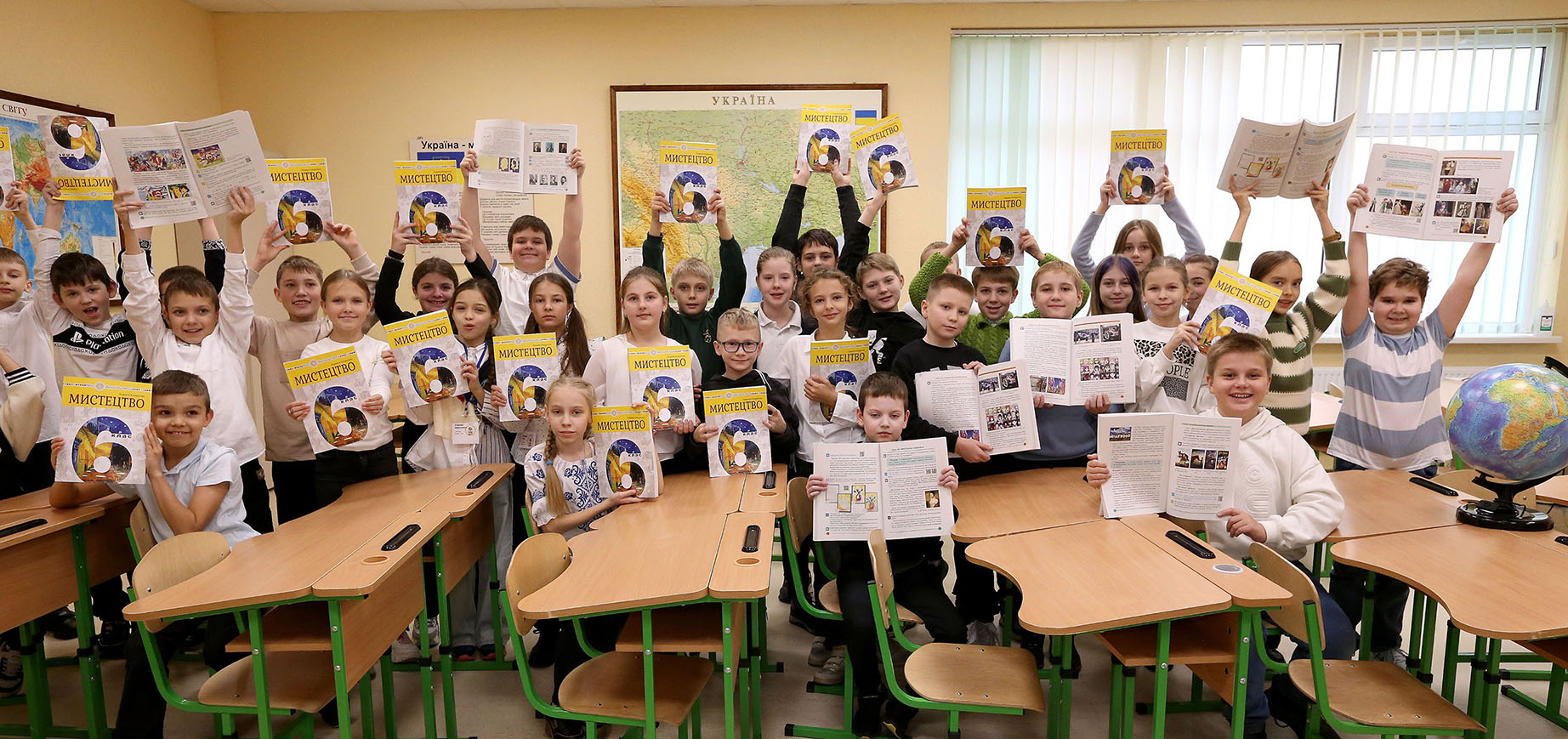 Eine Gruppe von Schulkindern in einem Klassenzimmer, die Lehrbücher hochhalten.