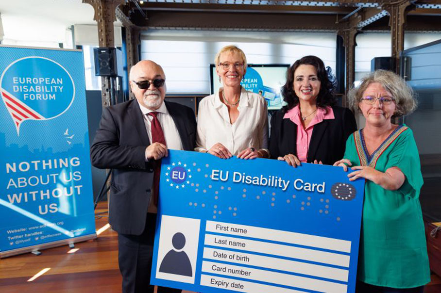 Helena Dalli und drei Vertreter des Europäischen Behindertenforums halten einen überdimensional großen EU-Behindertenausweis fest.