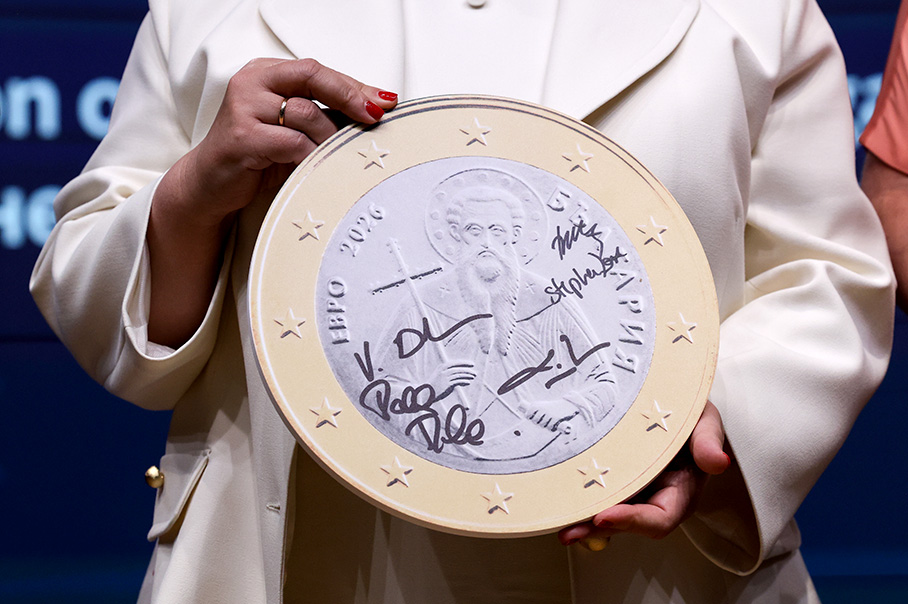 Žena drží veľkú maketu bulharskej jednoeurovej mince, na ktorej sú podpisy.