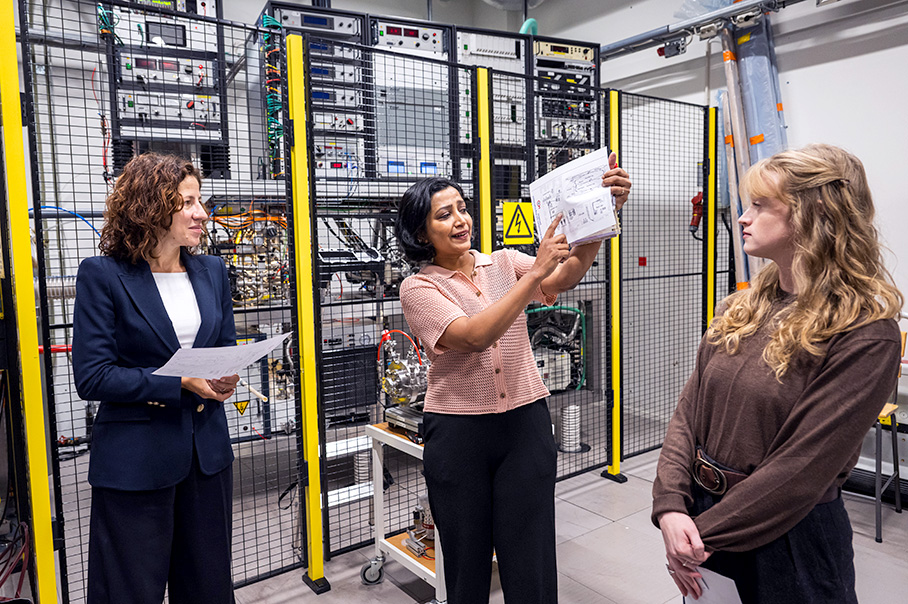 Roxana Mînzatu står framför ett antal servrar tillsammans med två kvinnor. En av kvinnorna håller upp ett papper.