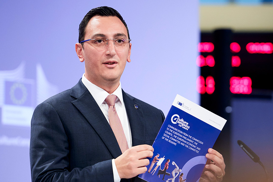Glenn Micallef står i en blå talarstol med en mapp med rubriken ”Culture Compass” (Kulturkompass). På skärmen bakom honom syns EU-kommissionens logotyp.