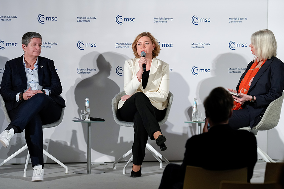 Η κυρία Χένα Βίρκουνεν, πλαισιωμένη από δύο άλλες γυναίκες, μιλά στο μικρόφωνο κατά τη διάρκεια συζήτησης πάνελ. Στον μεγάλο πίνακα πίσω τους επαναλαμβάνονται πολλές φορές τα αρχικά MSC και οι λέξεις, «Munich Security Conference» (Διάσκεψη του Μονάχου για την ασφάλεια).