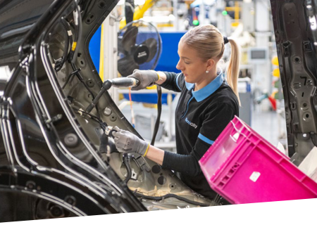 O angajată care lucrează pe o linie de asamblare într-o fabrică de automobile.