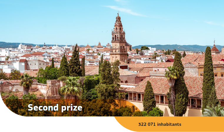 Trees and tiled rooftops at the Mosque-Cathedral of Córdoba with buildings and hills in the background.