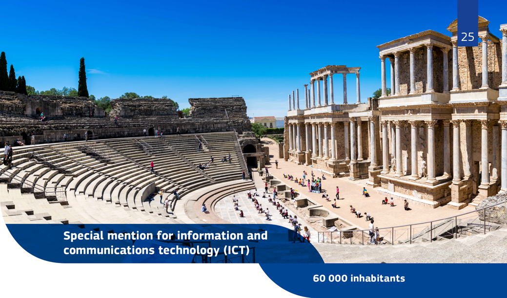 A landscape view of the Roman Theatre of Mérida with many visitors and bright blue sky.